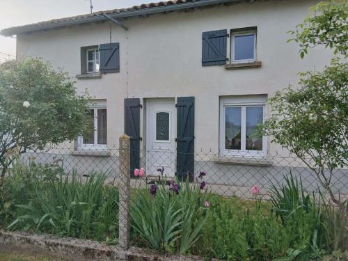 a white house with black windows and a fence at Gîte Chez Dédé in Brillac