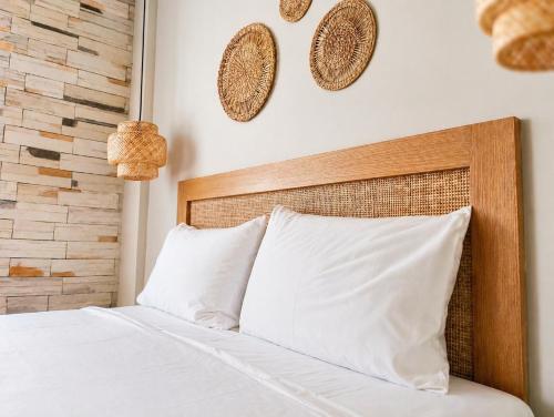 a bed with white pillows and two baskets on the wall at Lithos in Palaiochora
