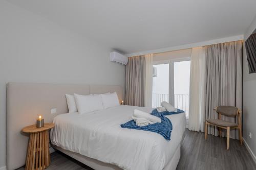 a bedroom with a large white bed with a window at Azor Signature Flats - IV in Ponta Delgada