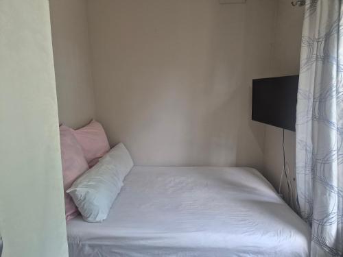 a small bedroom with a bed with white sheets and pillows at BluSash in Durban