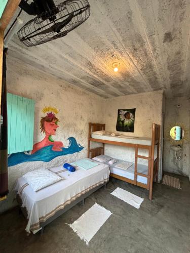 a bedroom with two beds and a painting on the wall at Hostel Flor da Vida in Canoa Quebrada
