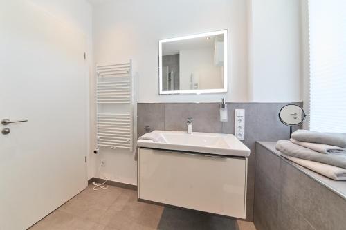 a white bathroom with a sink and a mirror at Burgblick Apartment Schieferblau in Bernkastel-Kues