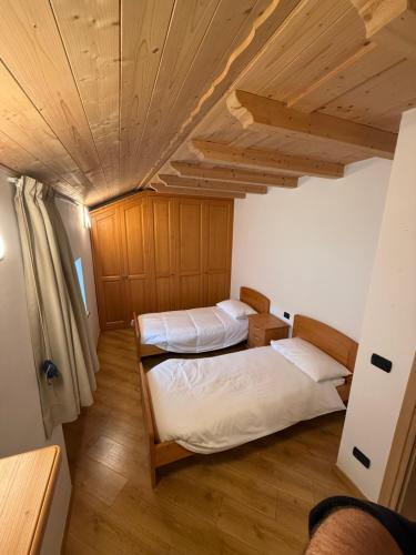 two beds in a room with a wooden ceiling at Casa singola zona pedonale Fiera di Primiero in Fiera di Primiero