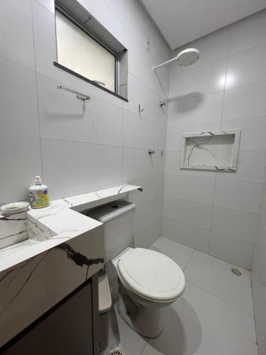 a white bathroom with a toilet and a sink at Casa aconchegante in Imperatriz