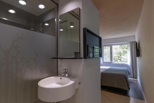 a bathroom with a sink and a mirror and a bed at Hotel Landgoed Zonheuvel in Doorn