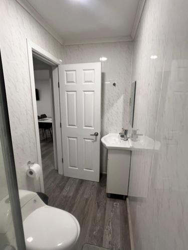 a bathroom with a toilet and a sink and a door at Refugio Austral in Punta Arenas