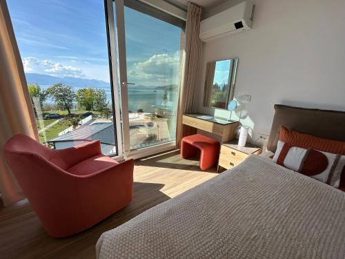a bedroom with a bed and a chair and a large window at SANI Apartments by Kanevce in Ohrid
