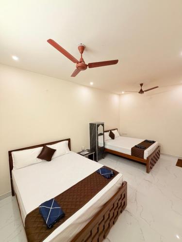 a bedroom with two beds and a ceiling fan at HARI HARA HOMEs in Rāmeswaram