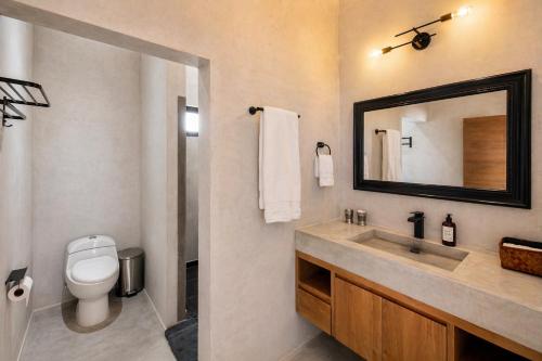 a bathroom with a toilet and a sink with a mirror at Ocean view terrace and saltwater pool group getaway in Todos Santos
