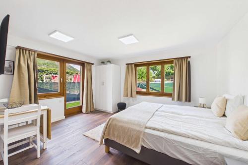 a bedroom with a bed and a desk and windows at Cozy Studio with a Garden in Gamsen