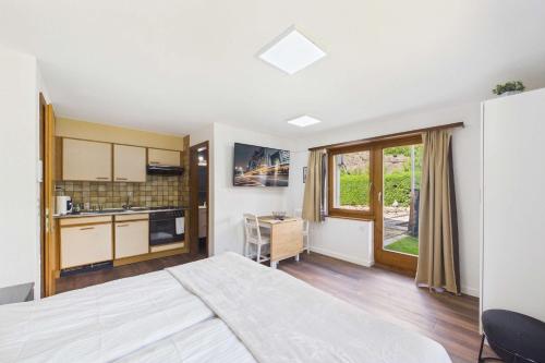a bedroom with a large bed and a kitchen at Cozy Studio with a Garden in Gamsen