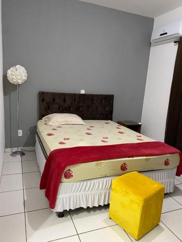a bedroom with a bed with a red blanket and a yellow stool at mazzonetto ap 03 in Primavera do Leste