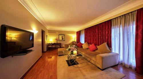 a living room with a couch and a television at Hotel Royal Orchid Bangalore in Bengaluru