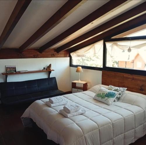 a bedroom with a large white bed and a window at Cabañas Abedul in Lago Meliquina