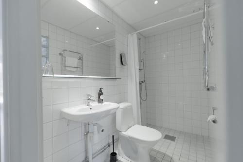 a white bathroom with a sink and a toilet at Hensbacka Hotell in Munkedal