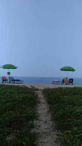 a group of picnic tables and umbrellas on the beach at Marari Babu Homestay in Mararikulam