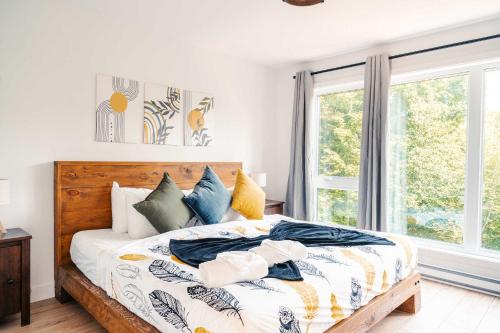 a bedroom with a bed with white walls and a window at Le Yéti de Tremblant in La Conception