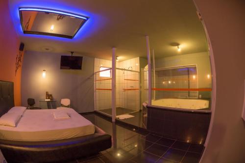a room with a tub and a bed and a mirror at La Passion Motel LTDA EPP in Jaú