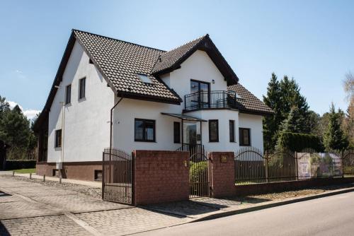 a white house with a black roof and a fence at Dom Nad Wodą - Smolarnia in Smolarnia