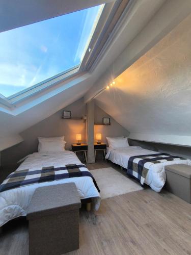 a attic bedroom with two beds and a large window at Pierres & prée Cocon de Charme et sa terrasse étoilée in Mettet