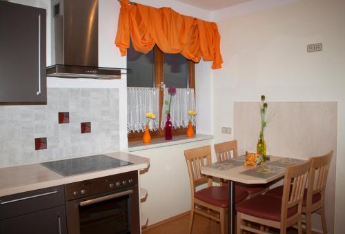 eine Küche mit einem Tisch, Stühlen und einem orangen Vorhang in der Unterkunft Frühstückspension Kuzmic in Wartberg