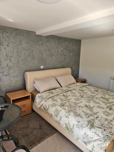 a bedroom with a bed and a table at Apartman Centar in Srbobran