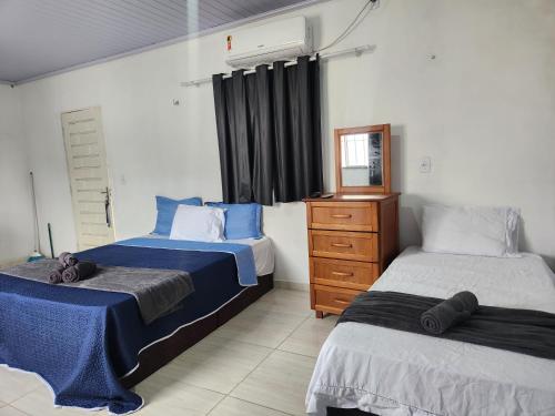 a bedroom with two beds and a dresser in it at Mini Apartamentos na entrada de Tutóia in Tutóia