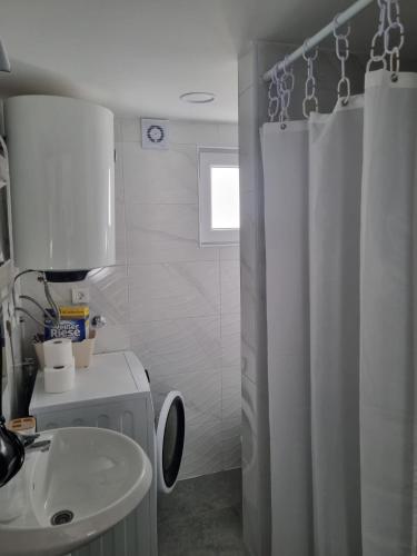 a bathroom with a white shower curtain and a sink at Apartmani 'Cvit' in Karlobag
