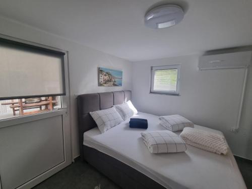 a bedroom with a bed with pillows and a window at Apartmani 'Cvit' in Karlobag