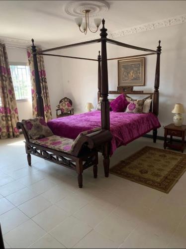 a bedroom with a canopy bed with a purple comforter at Linda's Guest House in Rotouma