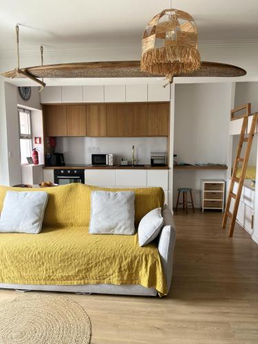 a living room with a yellow couch and a kitchen at Furadouro Cool & Cozy Flat in Furadouro