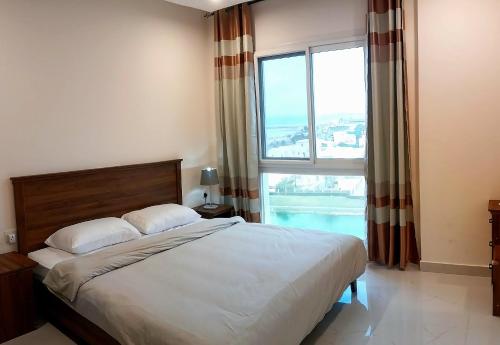 a bedroom with a large bed and a large window at Beach star residency 2 in Muscat