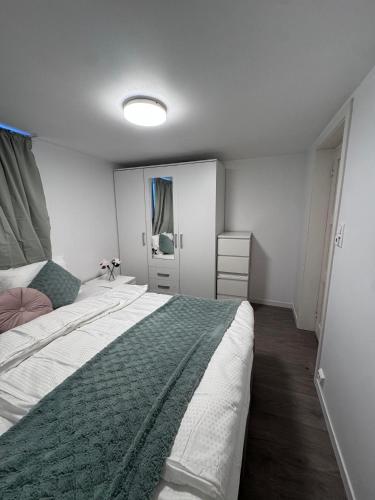 a bedroom with a large bed with a green blanket at Central leilighet i Kristiansand Vågsbygd in Kristiansand
