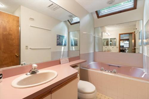 a bathroom with a pink tub and a sink at Split Rock Classic Chalet – Game Room & Family Friendly in Pocono Pines