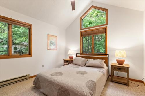 a bedroom with a bed and two windows at Split Rock Classic Chalet – Game Room & Family Friendly in Pocono Pines