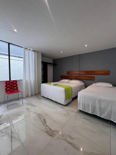 a bedroom with two beds and a red chair at Hotel Amazonas Real in Leticia