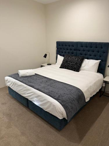 a large bed with a blue headboard in a bedroom at Belmore Living in Goulburn