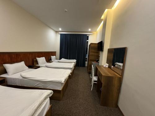 a hotel room with four beds and a desk at Koll Hotel in Erbil