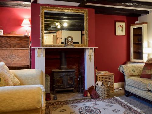 a living room with a fireplace and a mirror at Rebecca's Cottage in Ashby Saint Ledgers