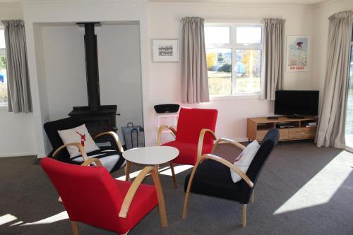 a living room with red chairs and a table at Matagouri Cottage - Lake Tekapo in Lake Tekapo