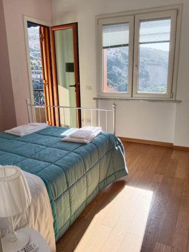 a bedroom with a bed with a blue comforter and two windows at White Stylish Apartment 4 in Vico Equense