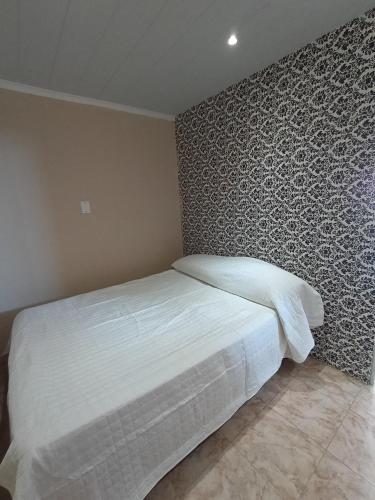 a bedroom with a white bed with a patterned wall at Espacio Pueyrredón in Comodoro Rivadavia