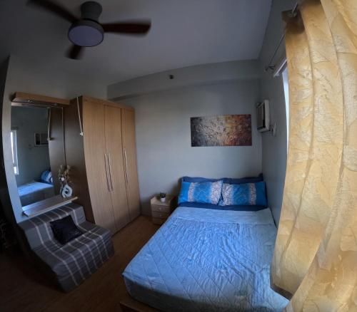 a bedroom with a blue bed and a couch at Mivesa Garden Residences Lahug in Cebu City