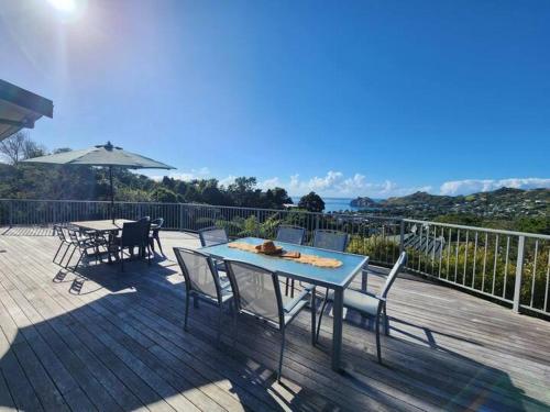 a wooden deck with a table and chairs on it at Cathedral Cove Retreat in Hahei