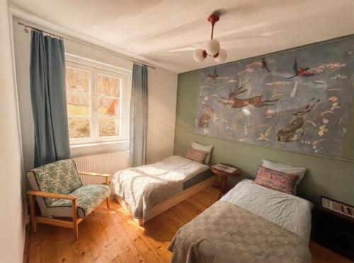 a bedroom with two beds and a chair and a painting at Gawra Bogusza in Lądek-Zdrój