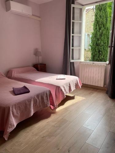 a bedroom with two beds and a large window at Mas Bérenger in Beaumes-de-Venise