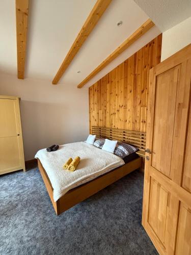 a bedroom with a bed with a wooden wall at Villa Montis in Vysoké Tatry