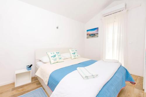 a white bedroom with a bed and a window at Apartments Mir in Duće