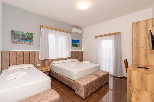a bedroom with two beds and a tv and a couch at Hotel Shkodra Comfort in Shkodër