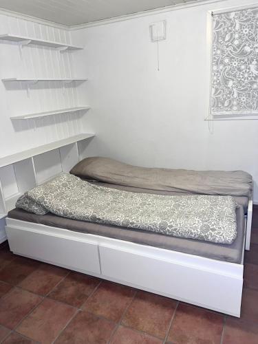 a small bed in a room with a shelf at Cozy apartment in Drammen